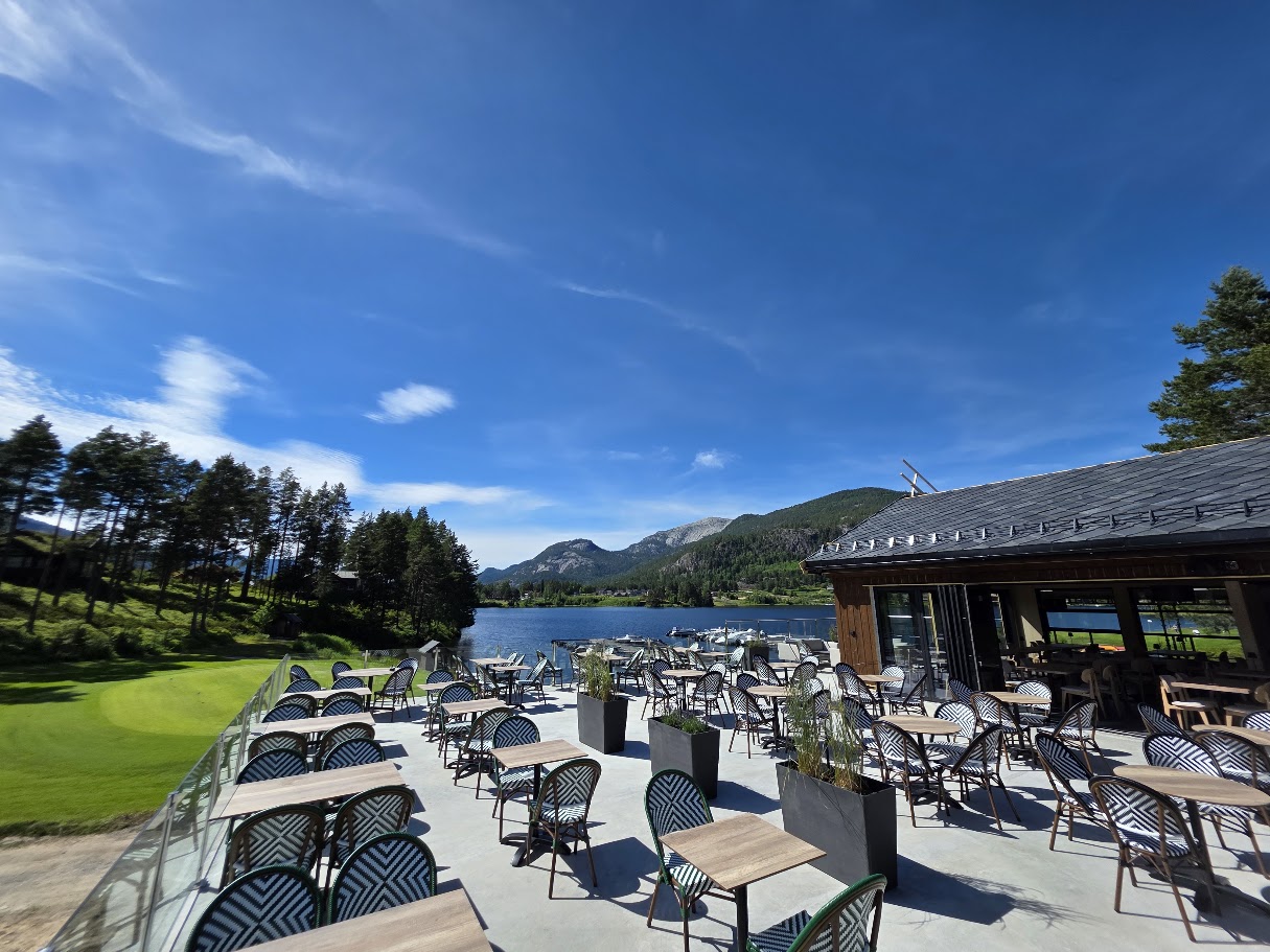Sommerterrassen ved klubbhuset med sittegrupper, utsikt over Nisser og fjellene