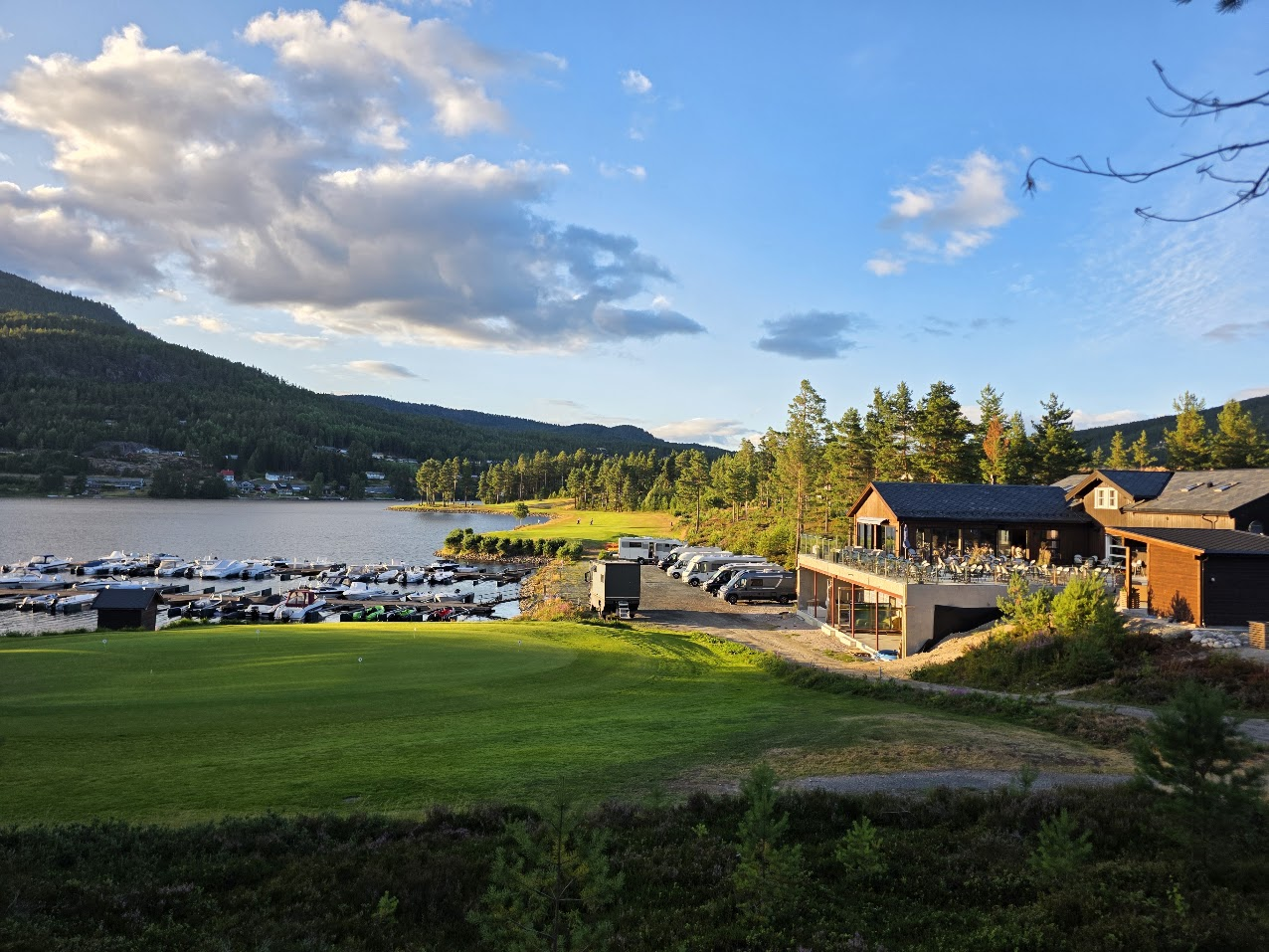 Klubbhuset på Vrådal Golf med bobiler, båthavn og Nisser ved siden av